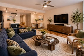 A living room with a dark blue couch, a coffee table, and a television on a wooden stand.