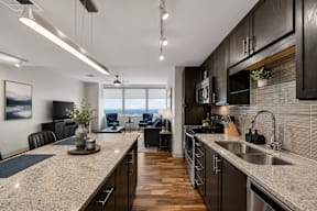 A modern kitchen with dark wood cabinets and granite countertops.