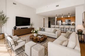 A modern living room with white furniture and a flat screen TV mounted on the wall.