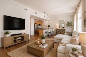 A modern living room with a flat screen TV, a coffee table, and a dining area in the background.