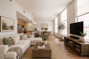 A living room with a white couch, a wooden coffee table, and a large window.
