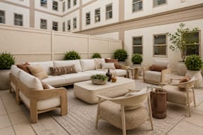 A patio with a white couch, chairs, and a coffee table.