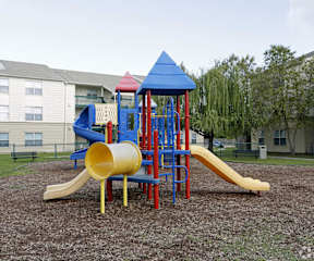 A playground with a yellow slide and a blue roofed structure.