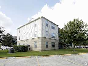 A two-story apartment building with a parking lot in front.