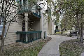 A small building with a balcony is surrounded by trees.
