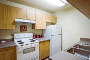 A kitchen with a white stove and a white refrigerator.