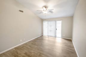 an empty living room with a ceiling fan and a window