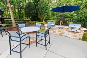 a patio with a bbq and a table and chairs