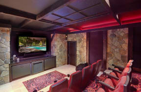 a media room with a large screen tv and a stone wall
