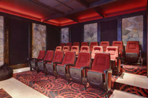 a room with a row of red chairs in front of a large stone wall
