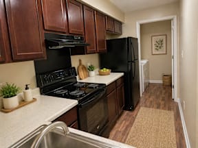 A kitchen with black appliances and wooden cabinets.