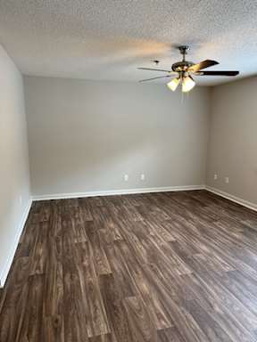 A room with a ceiling fan and wooden flooring.