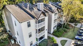 An aerial view of a white apartment building with a brown roof and a parking lot in front. at The Point at Perimeter, Georgia, 30338
