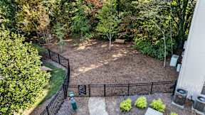 A backyard with a black fence and a green trash can. at The Point at Perimeter, Georgia, 30338