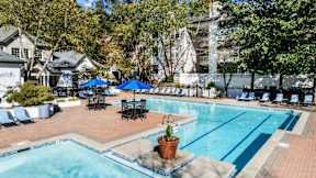 A pool area with a blue umbrella and chairs. at The Point at Perimeter, Georgia, 30338