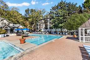 A large outdoor swimming pool surrounded by a brick patio and trees. at The Point at Perimeter, Georgia, 30338