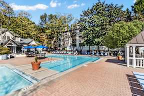 A large outdoor swimming pool surrounded by a brick patio and trees. at The Point at Perimeter, Georgia, 30338