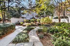 A pathway leads through a landscaped area with a building in the background. at The Point at Perimeter, Georgia, 30338