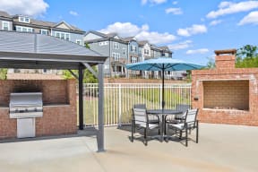 a patio with a grill and a table and chairs