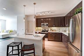 A modern kitchen with a white island and dark brown cabinets.