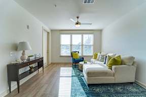 A living room with a couch, a table, a lamp, and a window.