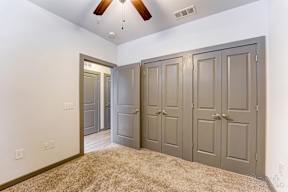 A room with a ceiling fan and three doors.