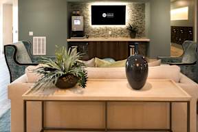 A living room with a white couch, a wooden coffee table, and a TV mounted on the wall.