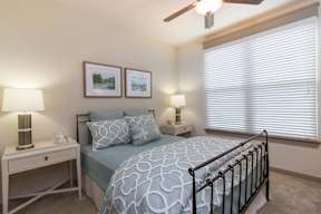 A bedroom with a bed, nightstand, and lamp.