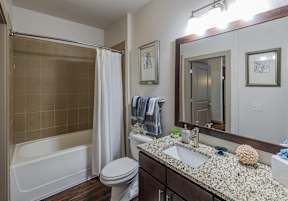 A bathroom with a white toilet, a sink, a bathtub, and a mirror.
