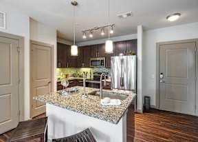 A modern kitchen with granite countertops and stainless steel appliances.