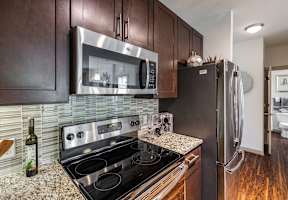 A modern kitchen with dark wood cabinets and stainless steel appliances.