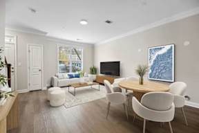A living room with a white couch, a wooden table, and a television.