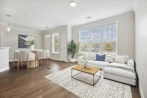 A living room with a white couch, a wooden coffee table, and a rug.