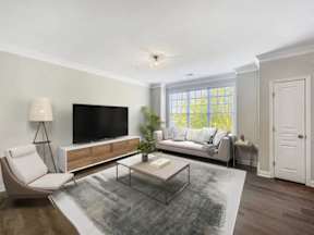 A modern living room with a white sofa, a glass coffee table, and a television.