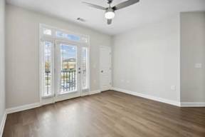 A room with a ceiling fan and a door leading to a balcony.