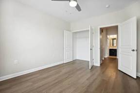 A room with a ceiling fan and light, and a doorway leading to another room.
