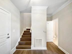 A white door is on the left of a staircase with a white column on the right.