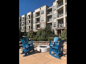 Two blue chairs are placed on a patio in front of a building.