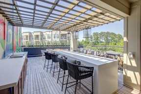A patio with a white counter and black chairs.