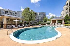 A large outdoor swimming pool surrounded by lounge chairs and umbrellas.