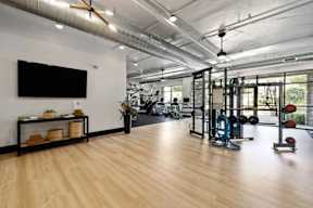 A gym with a variety of equipment including a treadmill, weights, and a television.