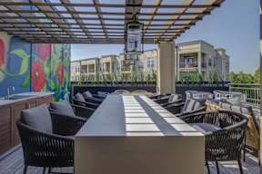 A patio with a table and chairs is set up on a wooden deck.