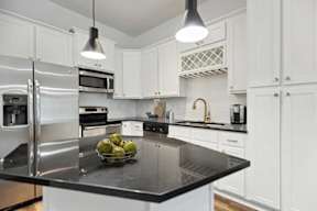 A modern kitchen with a black countertop and stainless steel appliances.