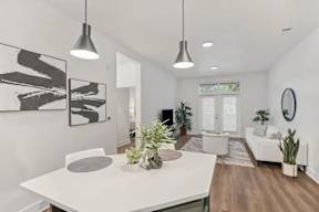 A modern living room with a white dining table and a large abstract painting on the wall.