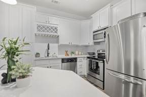 A kitchen with white cabinets and a stainless steel refrigerator.