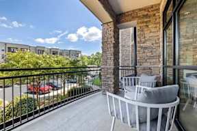 A balcony with a white chair and a stone pillar.