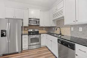 A kitchen with white cabinets and a black countertop.