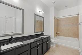 A bathroom with a black vanity and a white bathtub.