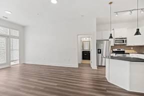 A kitchen with white cabinets and a black fridge.