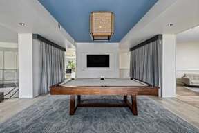 A modern living room with a pool table and a television.